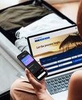 person using phone and laptop to book a trip