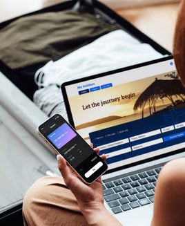 person using phone and laptop to book a trip