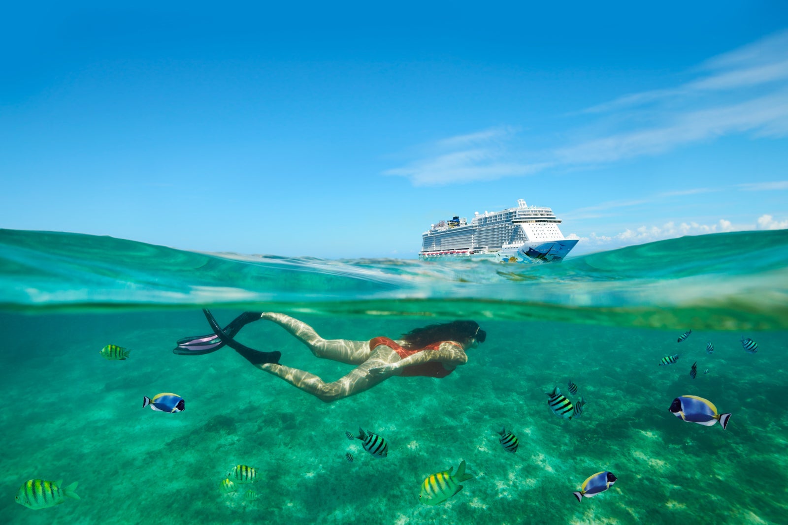 woman snorkeling in front of NCL cruise ship
