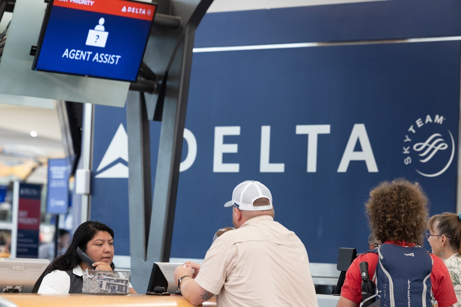 People speaking to a representative at a Delta Air Lines counter at Hartsfield-Jackson Atlanta International Airport