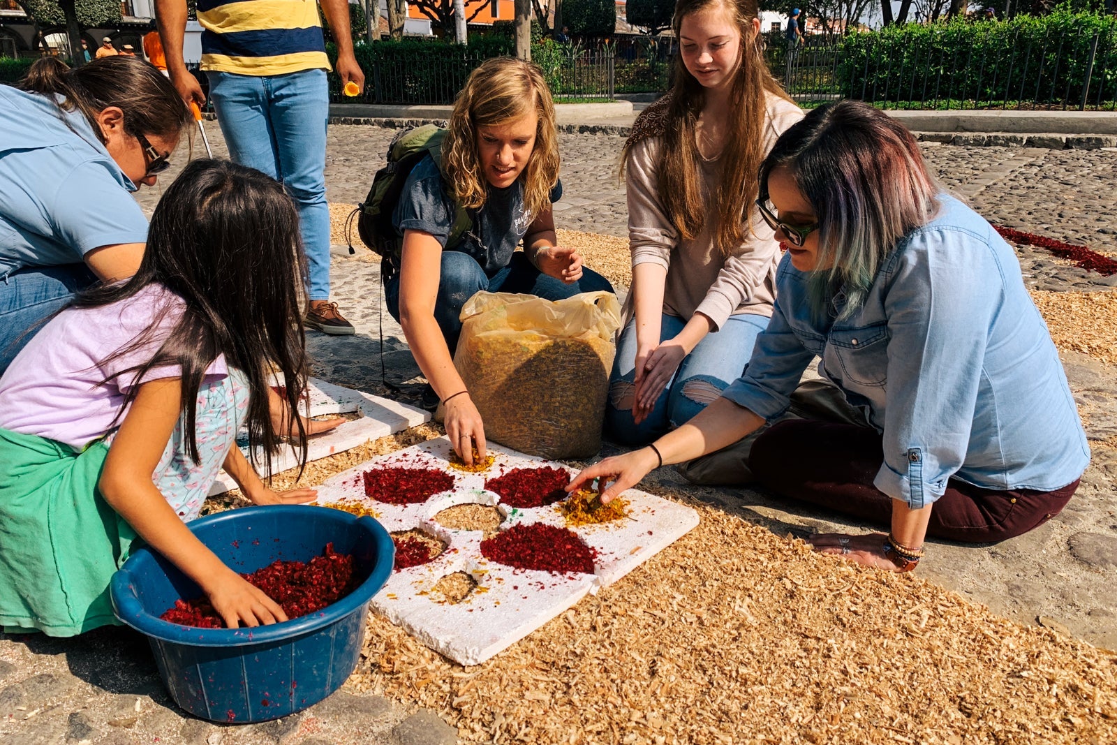 group of people help make a floral pattern on the square in Antigua