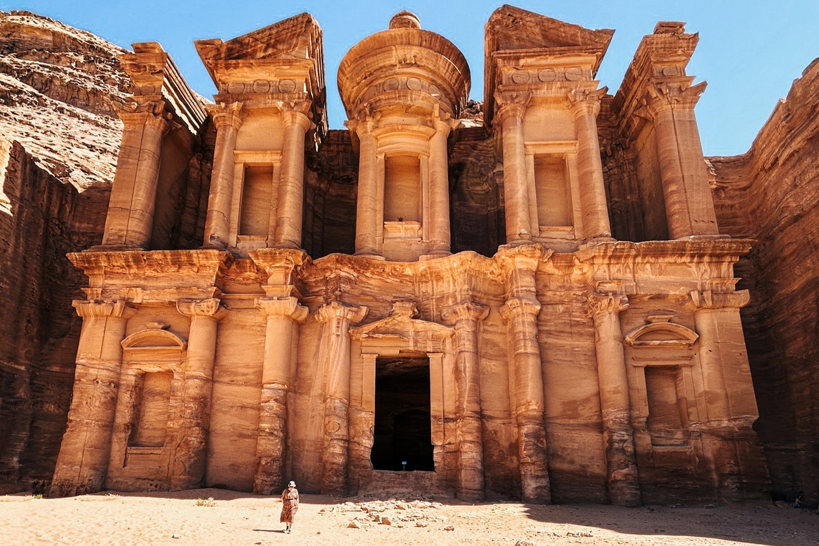 A close up of the Monastery structure at Petra with a woman in the foreground