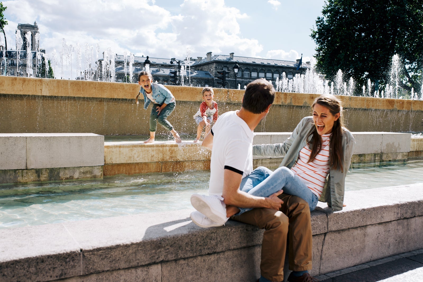 Family playing in water fountain
