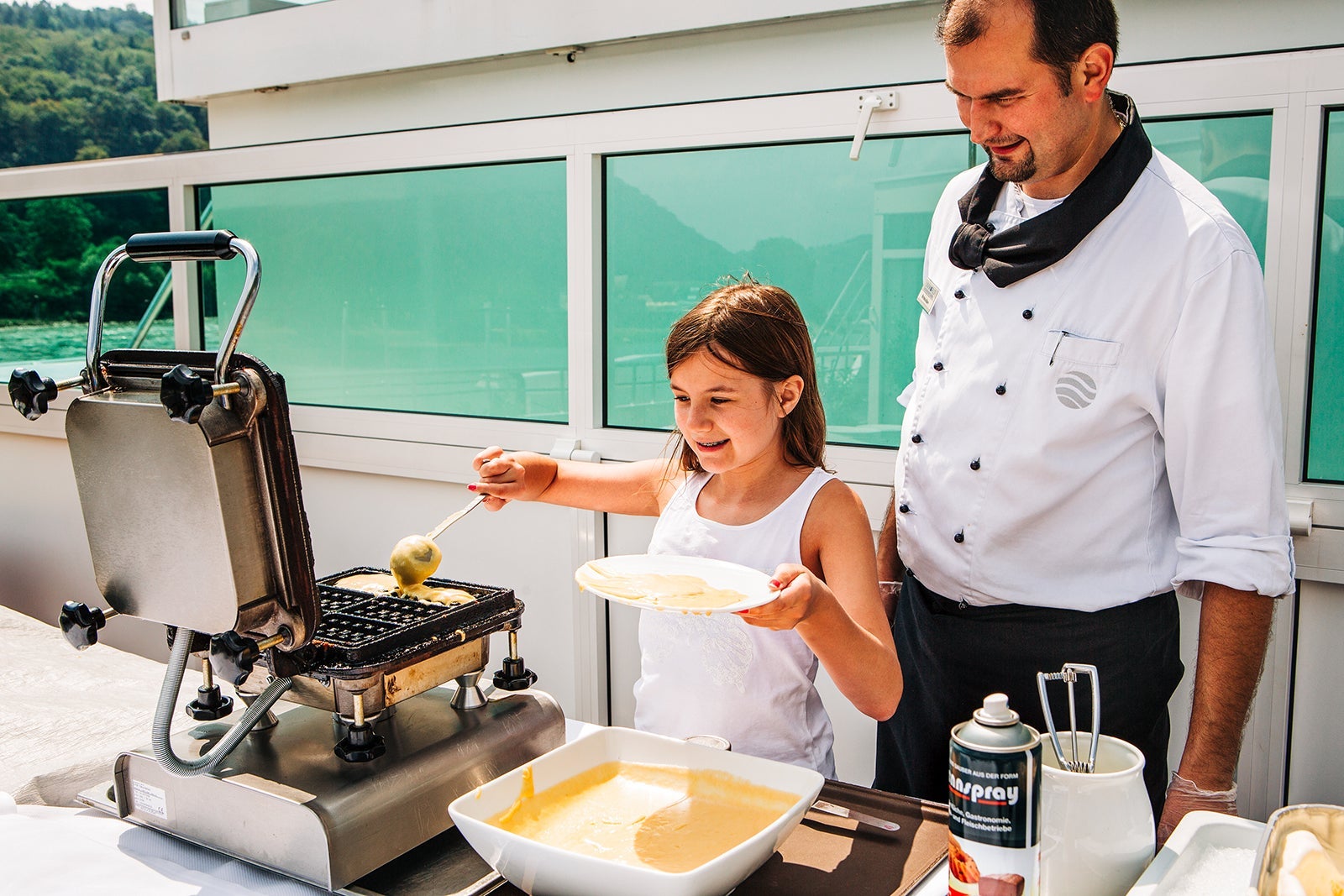 Young cruise passenger makes waffles with chef