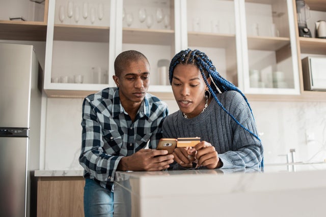 two people sitting and looking down at a credit card
