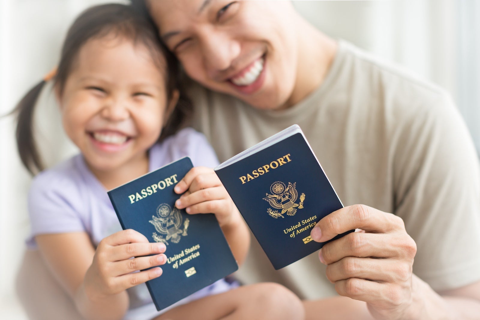 Asian dad and daughter holding amercian passports with pride.