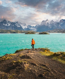 man hiking in front of blue lake and mountains in Chile