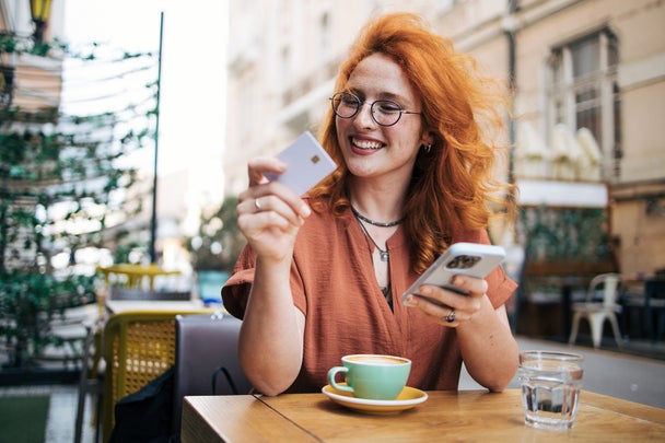 Happy young redhead woman  in cafe  drinking coffee and shopping online on smart phone
