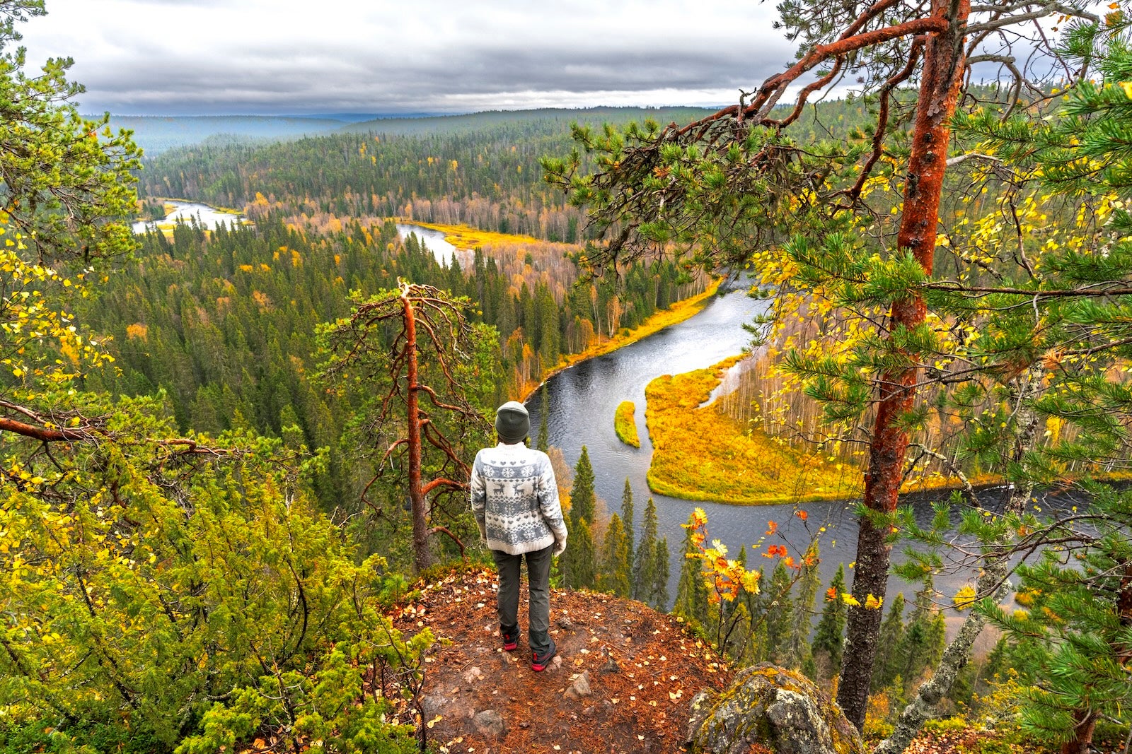 Person enjoys fall view from a top a mountain overlooking a river.