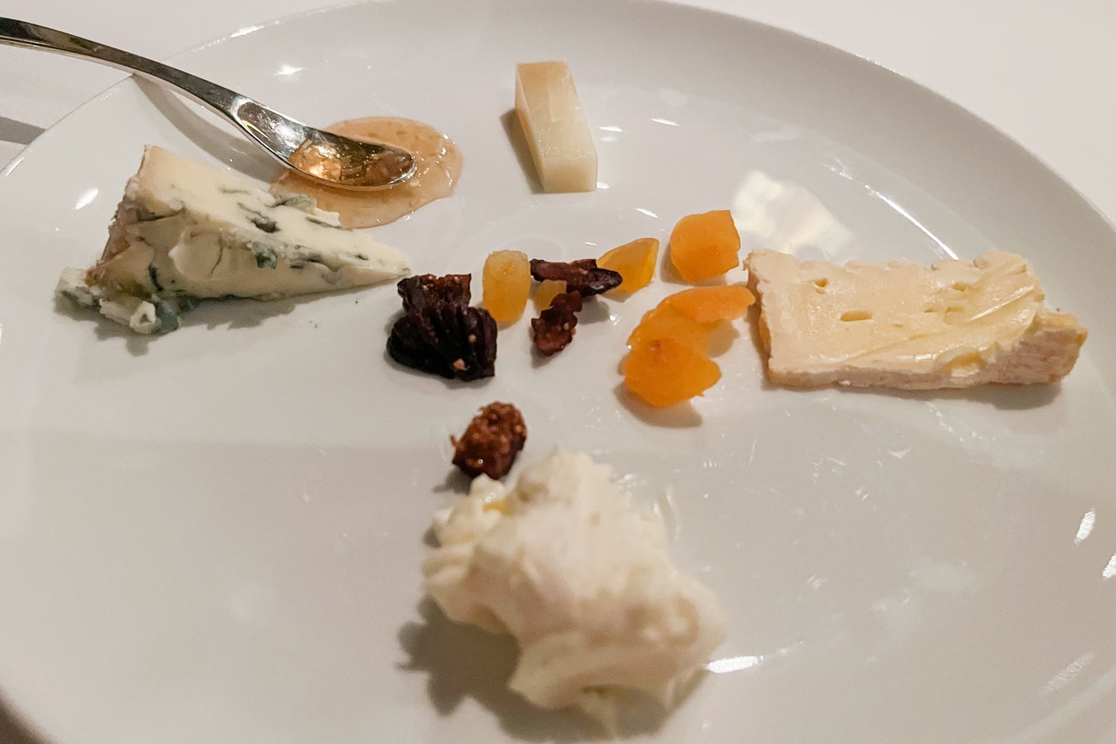 Selection of cheeses and dried fruit on a white plate