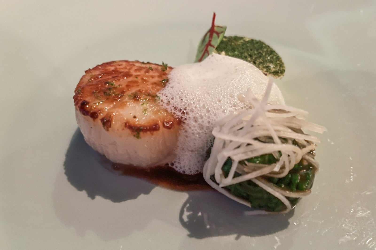 Plate with scallop, white foam and green sauce