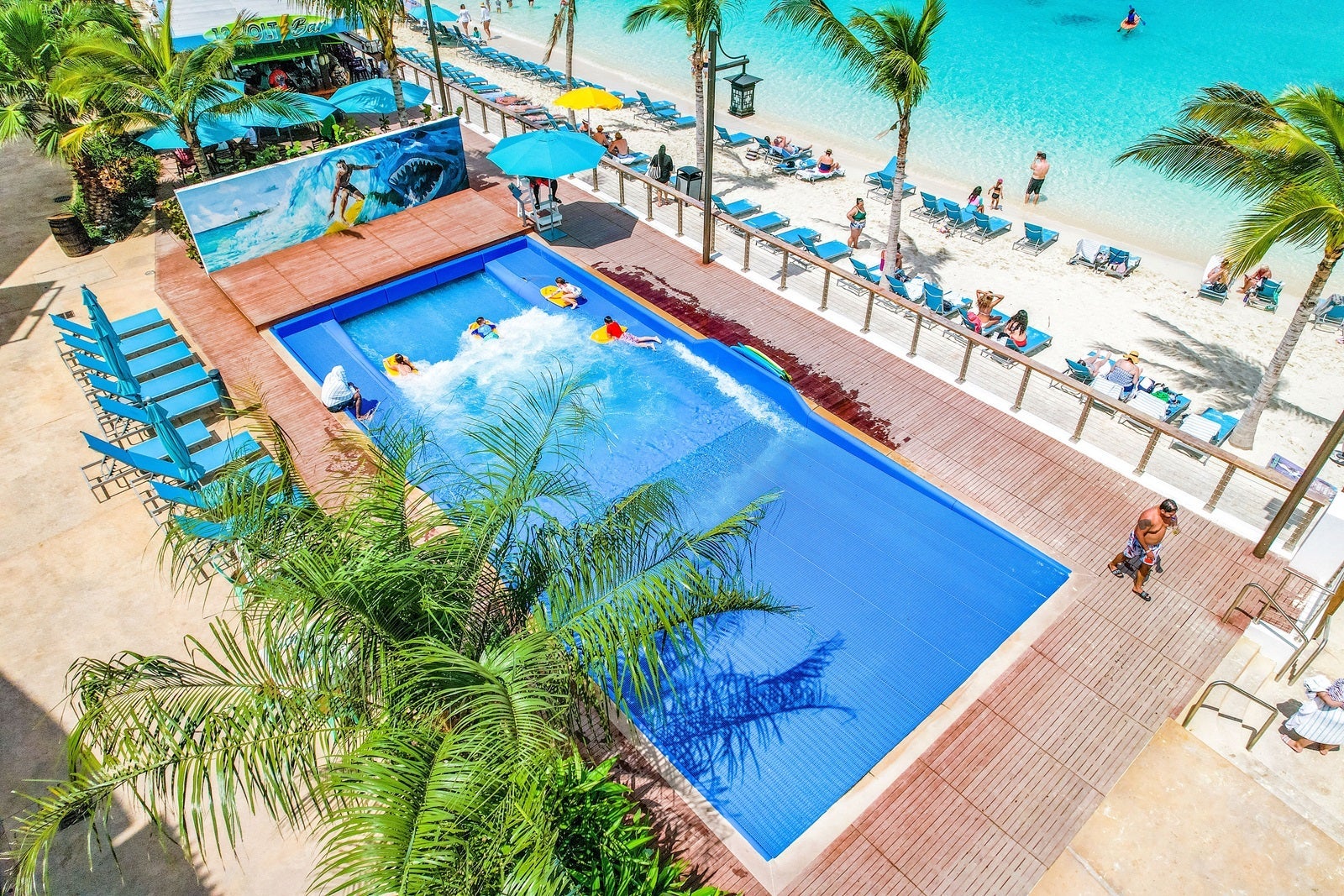 A surf simulator at a resort surrounded by palm trees