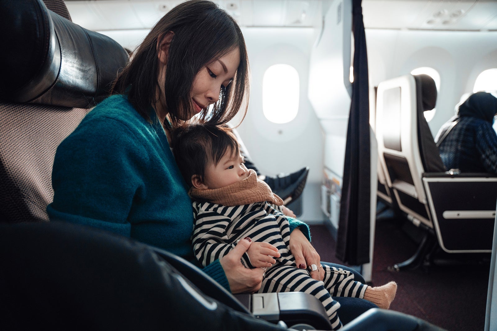 Woman holding child while sitting in a plane