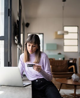 Woman holding a credit card and using her laptop