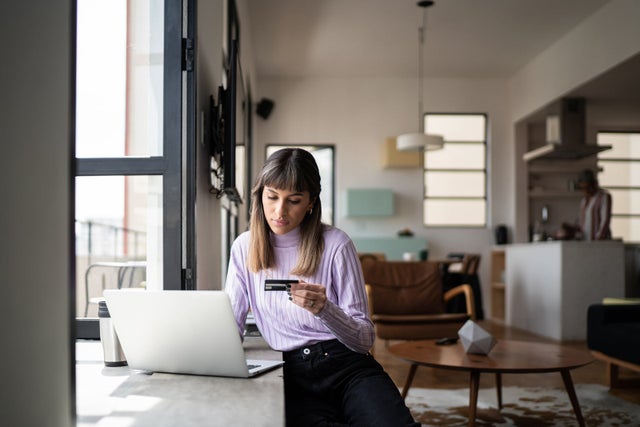 Woman holding a credit card and using her laptop