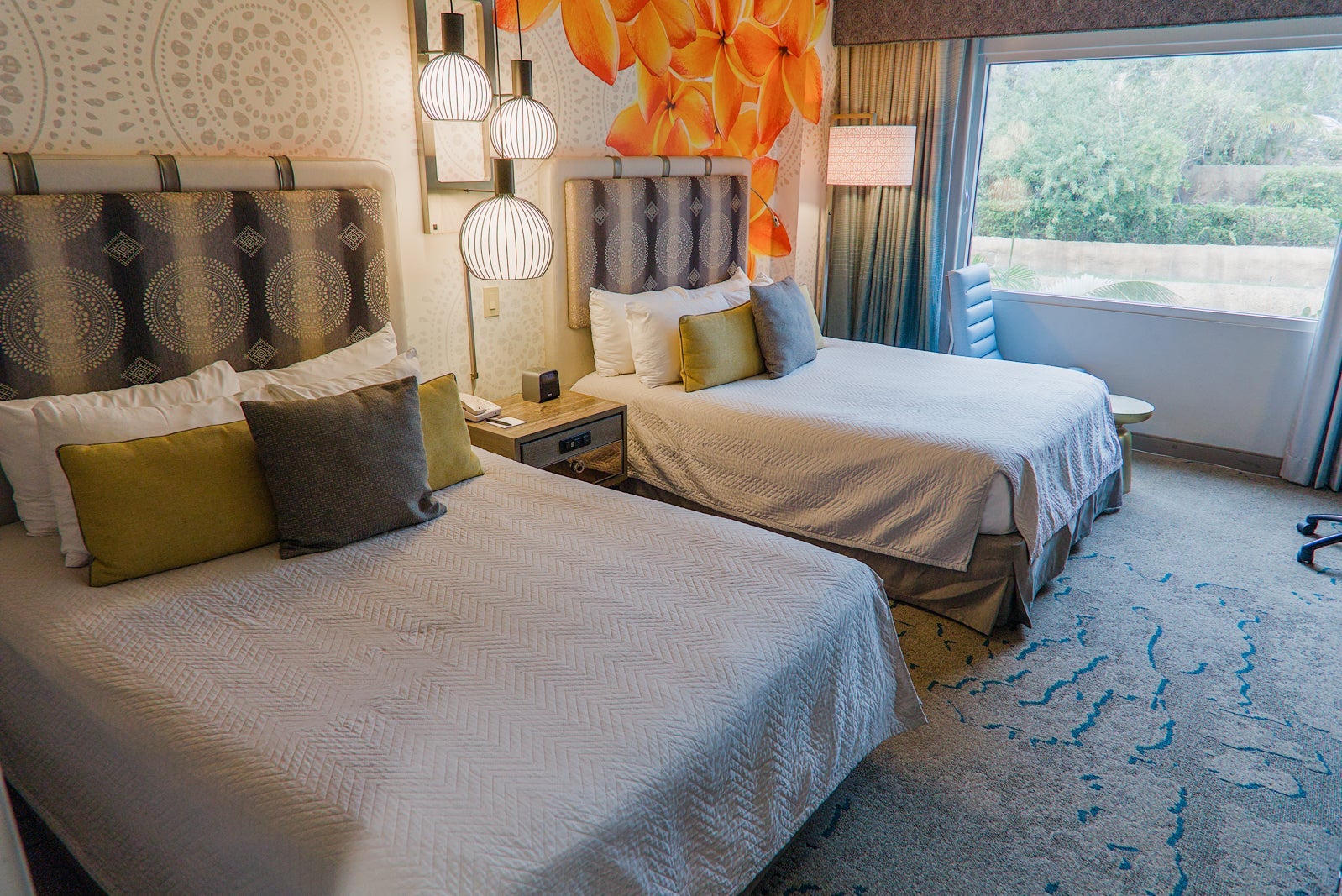 Two hotel beds with floral mural on the wall