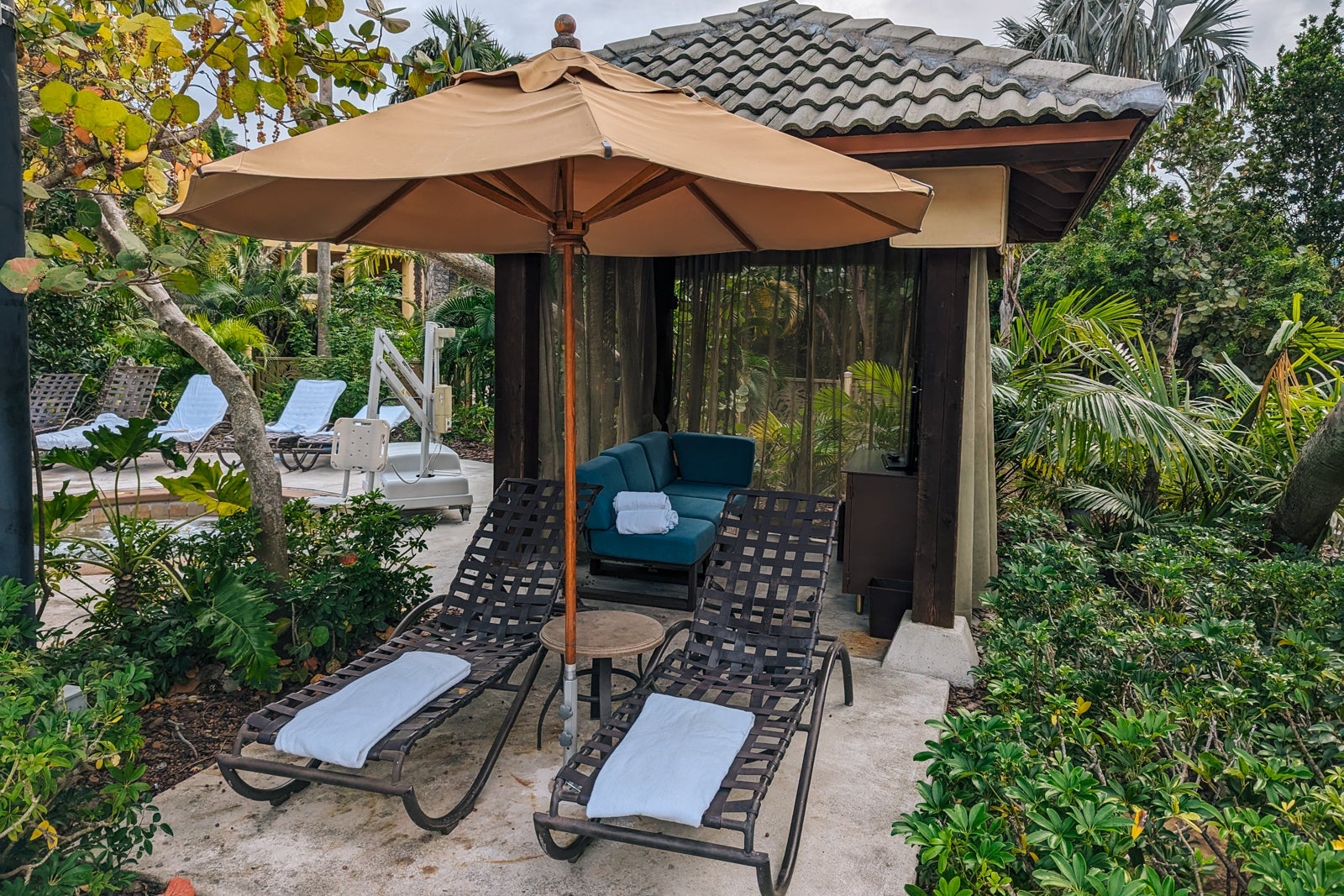 cabana by hotel pool with loungers and umbrella