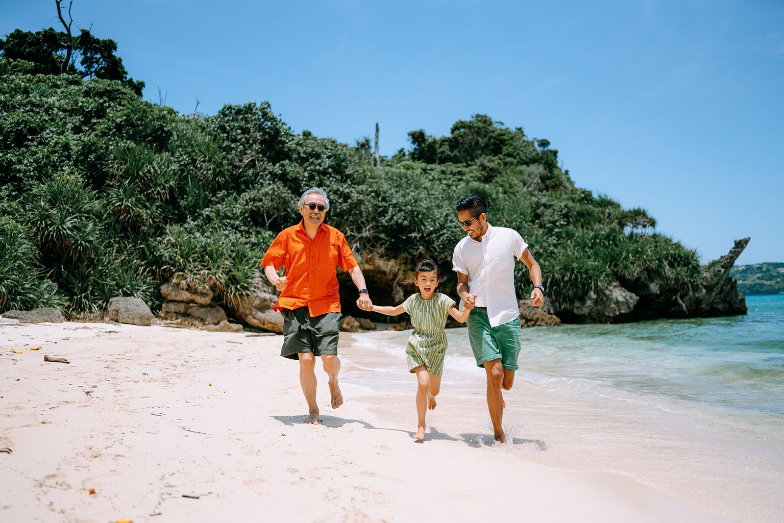 Three generation family running together on tropical beach