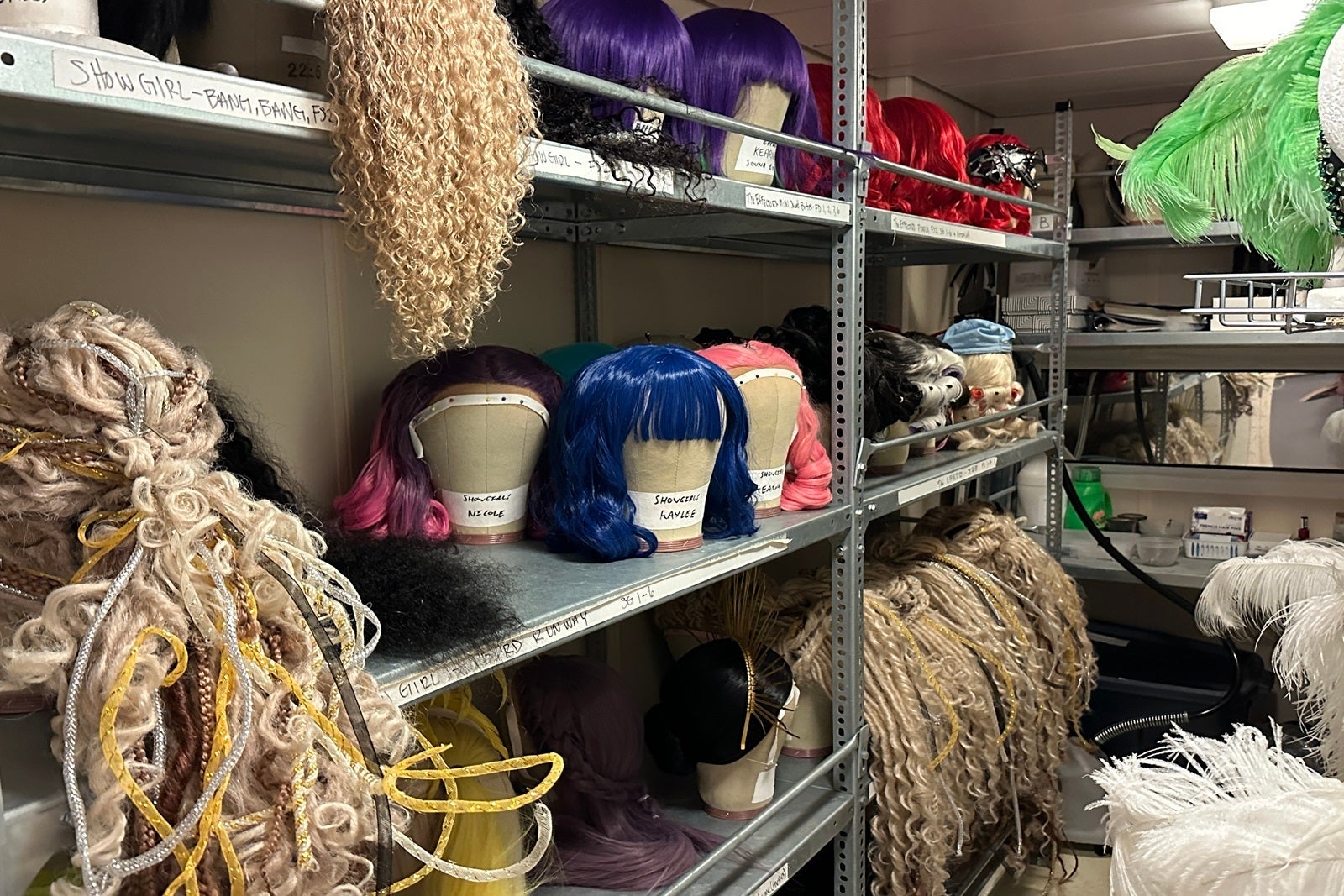 Shelves with a selection of colorful wigs on mannequin heads