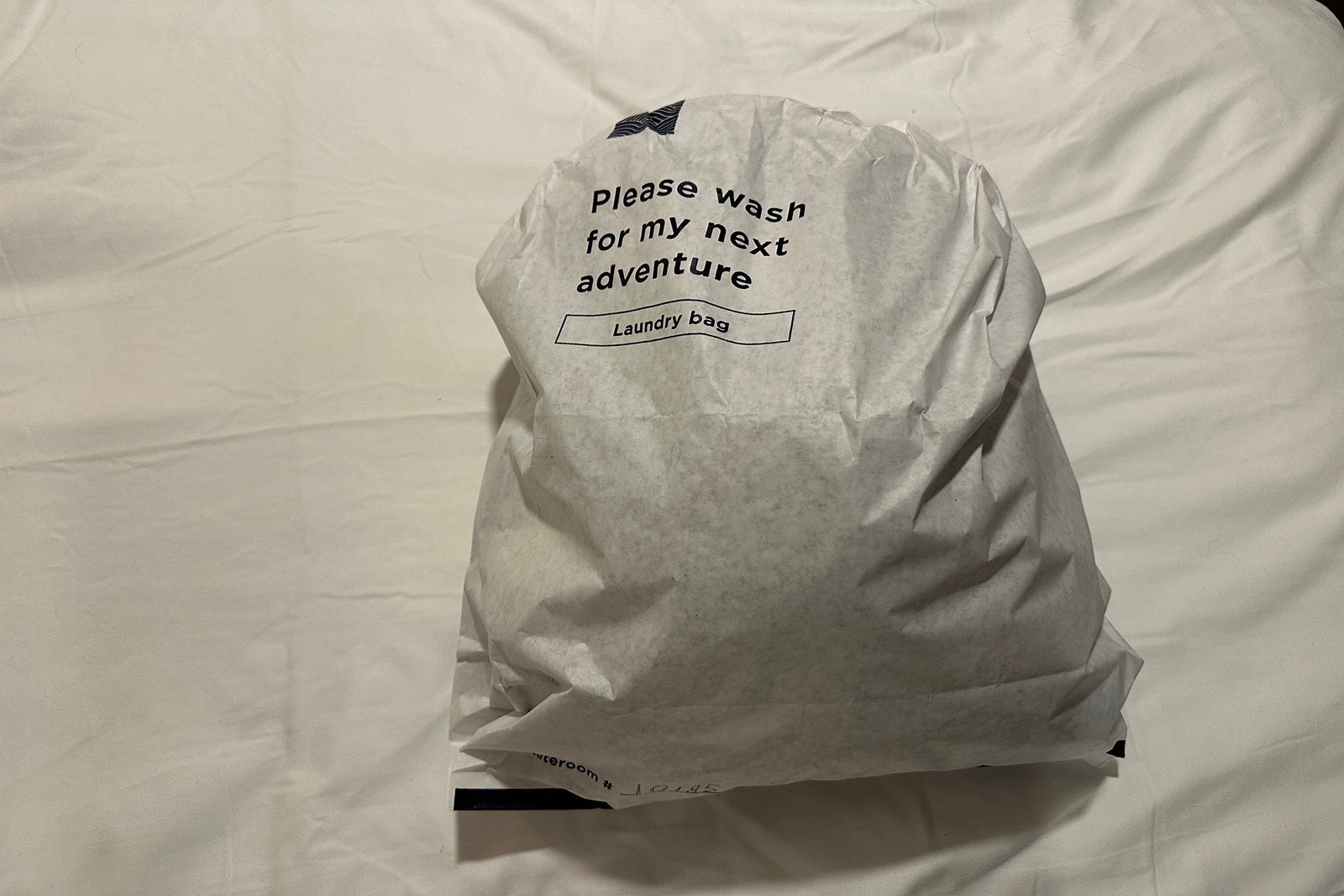 A full bag of laundry sitting on top o fa bed