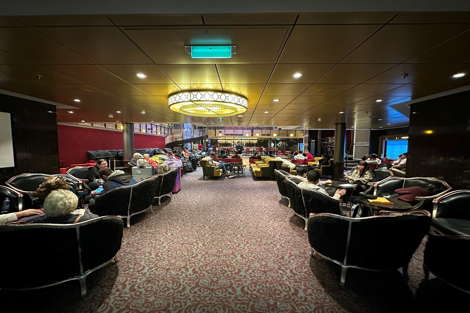A cruise ship lounge with passengers waiting to disembark the vessel