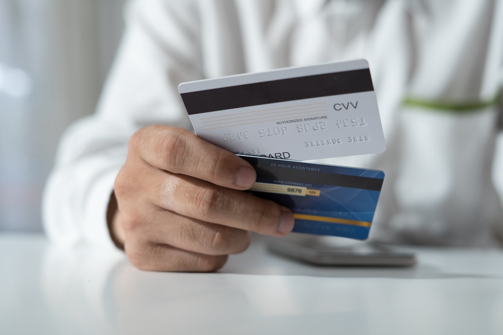 Hand hold two credit cards, seemingly making a choice