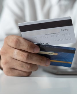 Hand hold two credit cards, seemingly making a choice
