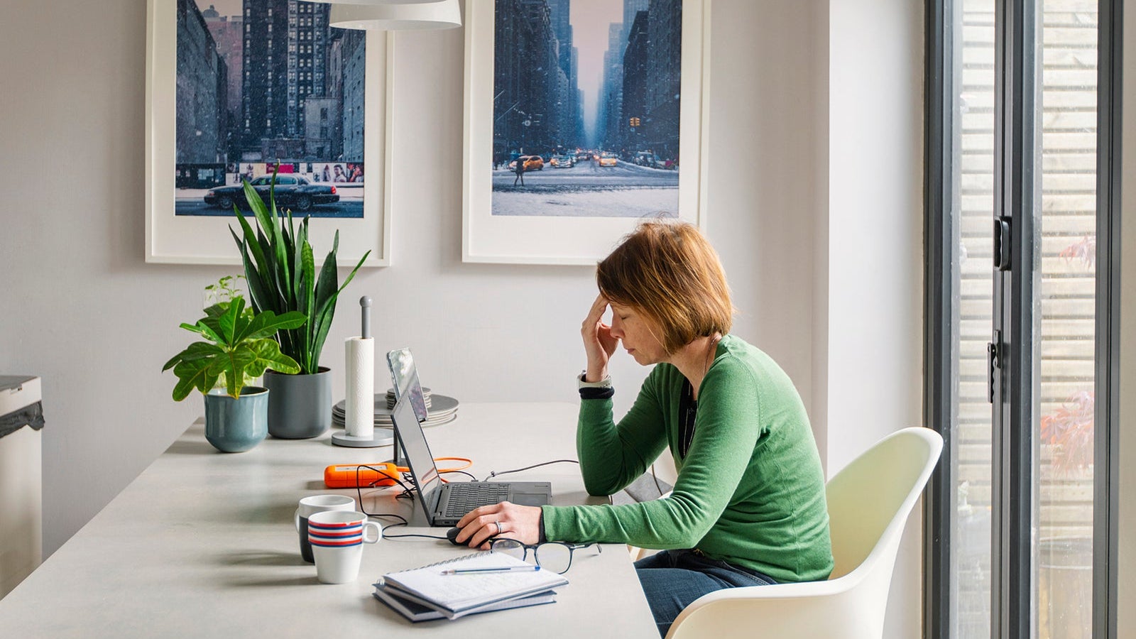 A stressed mature woman works from her dining table at home