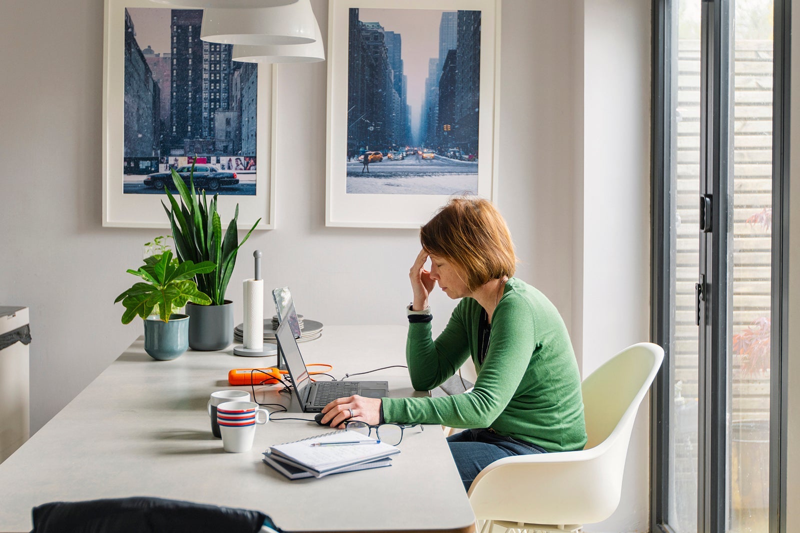 Stressed woman sitting at a table with a laptop.