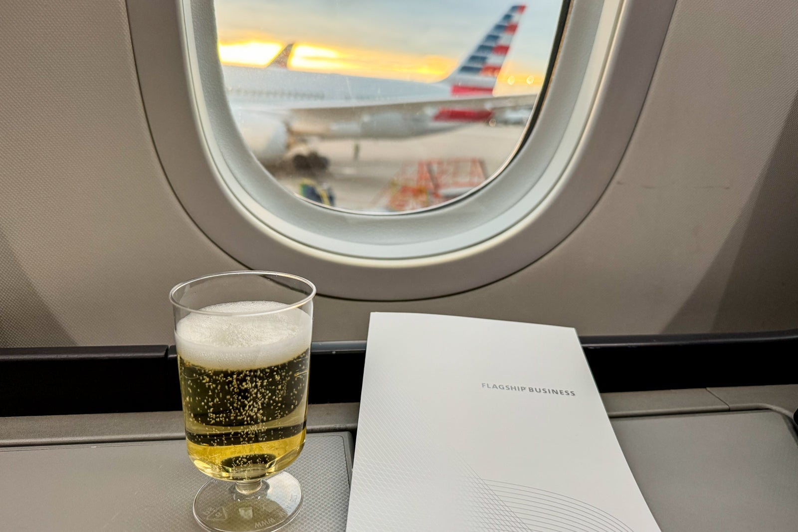 Why I've kept this American Airlines credit card in my wallet for years a glass of Champagne sitting on a tray in front of an airplane window