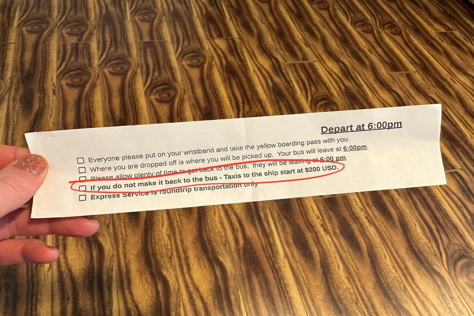 A hand holding a piece of paper with instructions, including taxi pricing