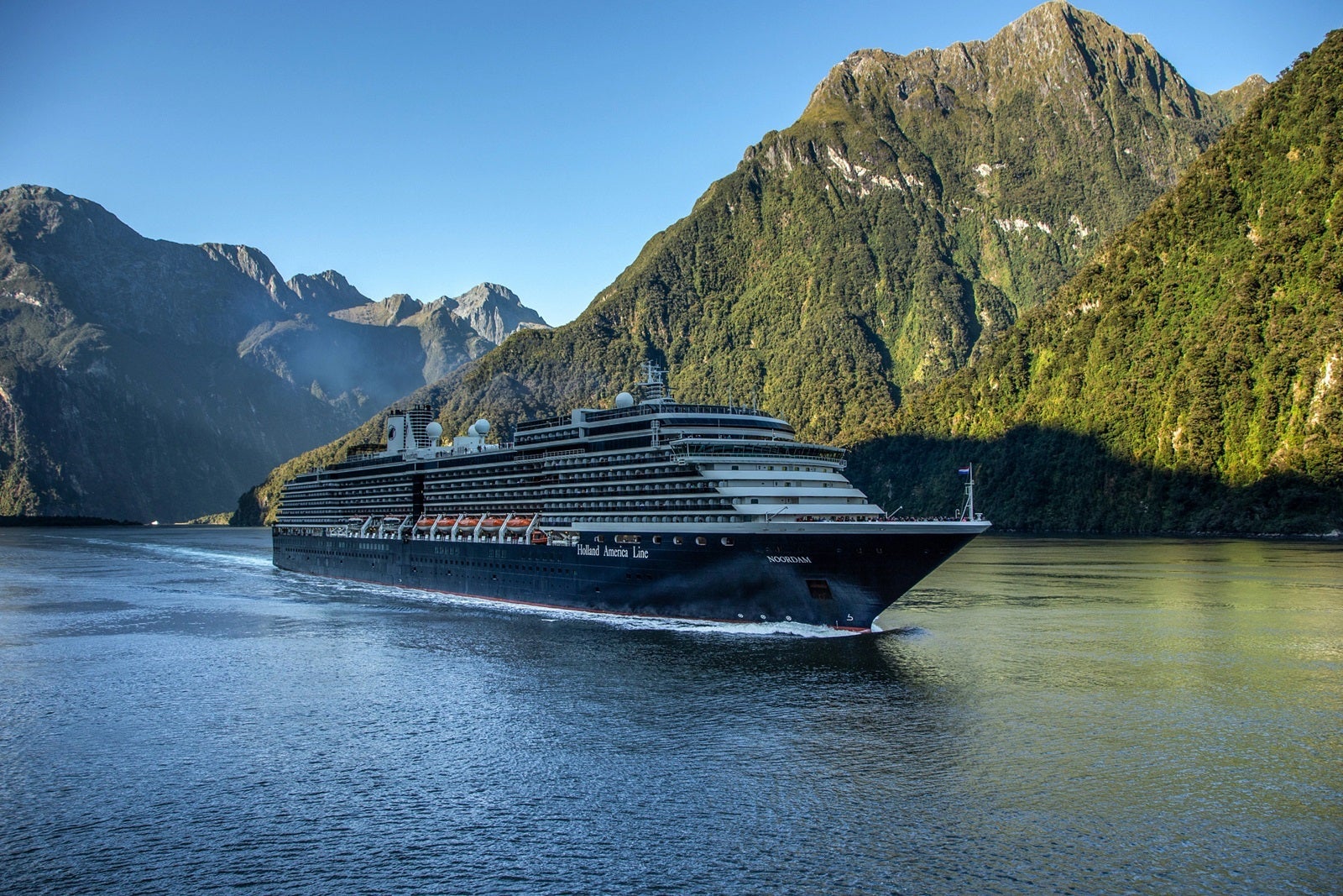 A cruise ship sails past a mountain in New Zealand