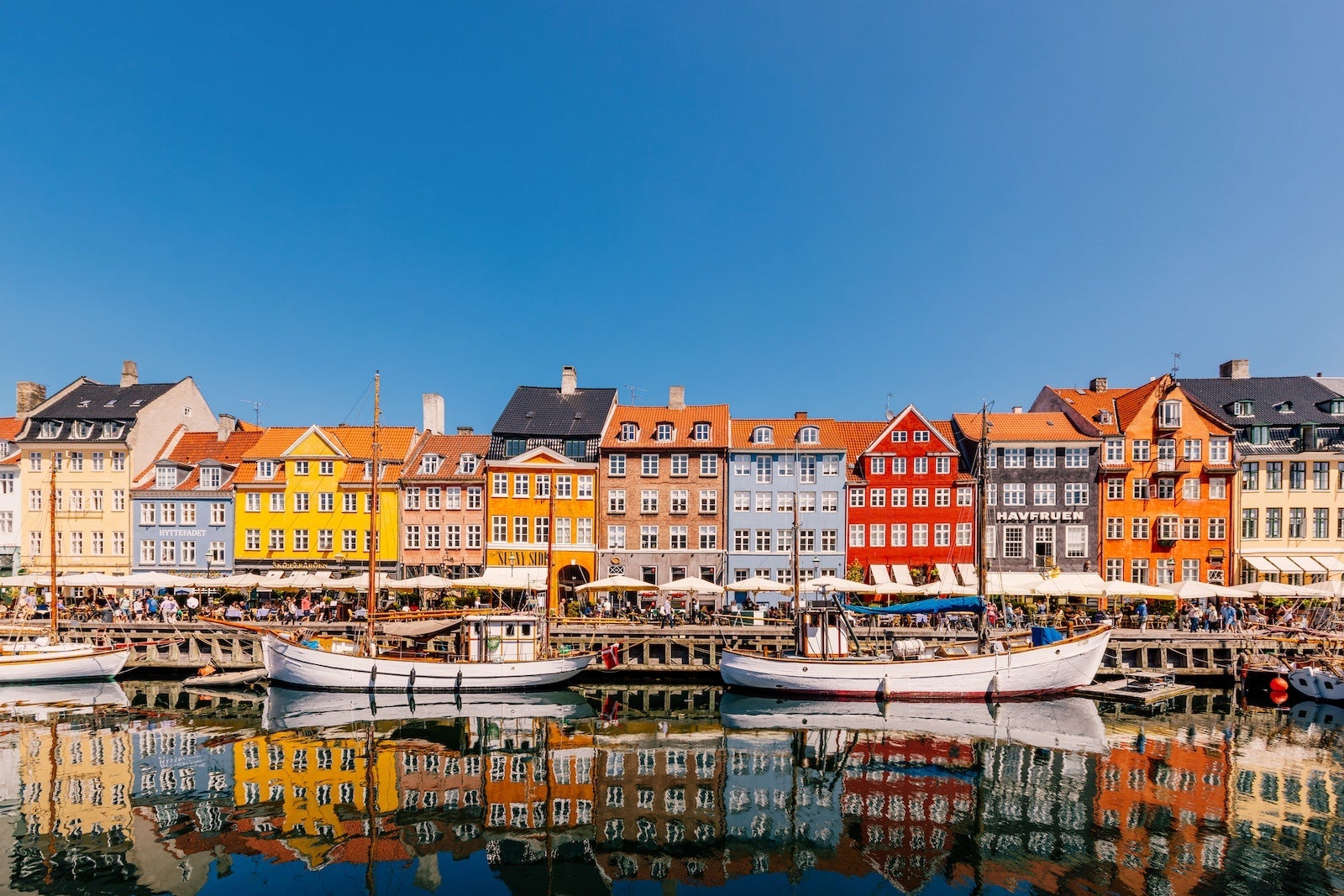 Multi-colored vibrant houses along Nyhavn harbour on a sunny day with clear blue sky, Copenhagen, Denmark