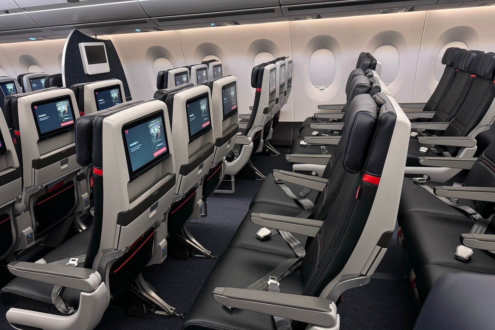 rows of dark blue and gray airplane seats with screens on the back