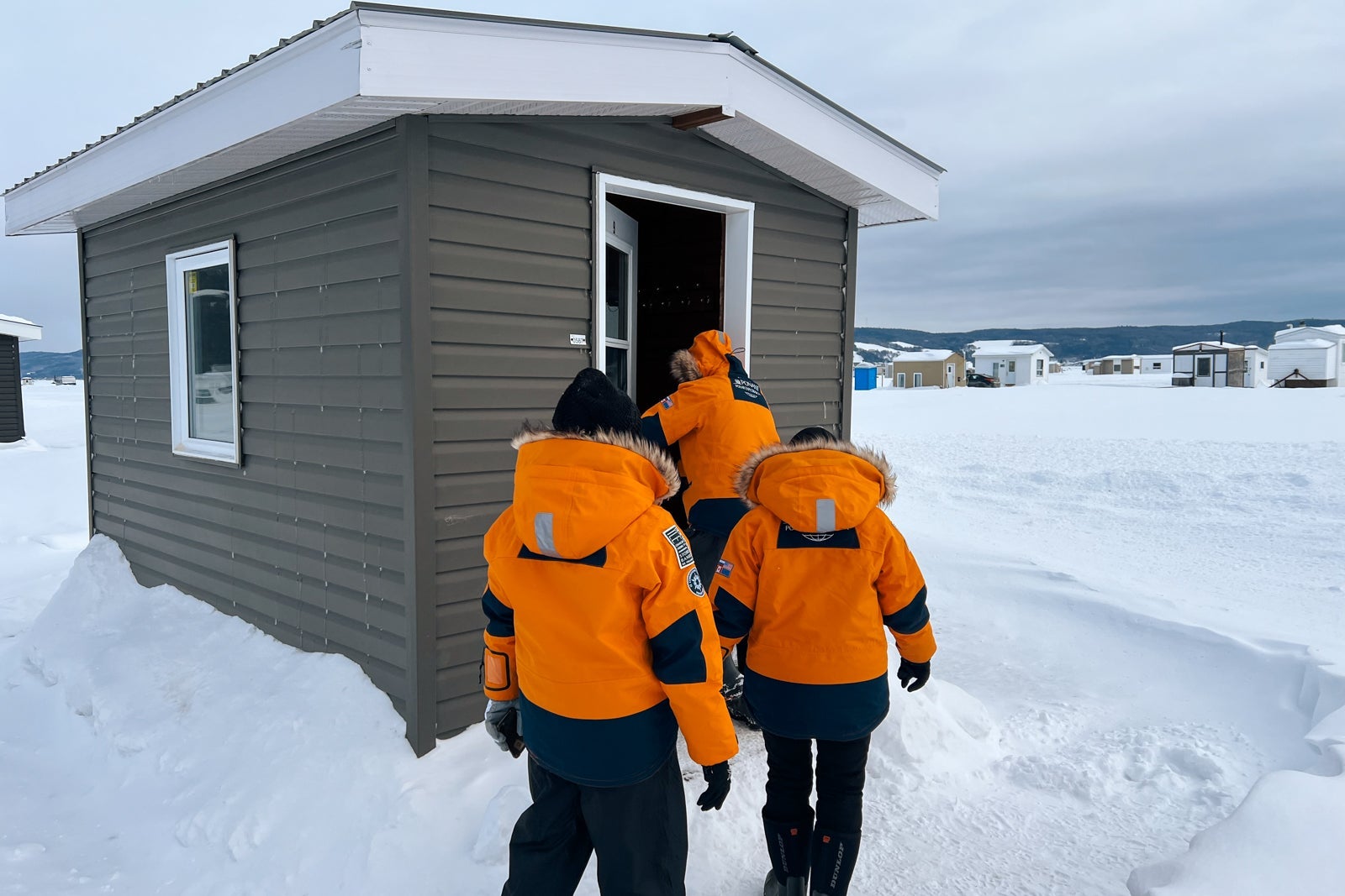 Le Commandant Charcot passengers enter an ice fishing hut set up on the ice of Saguenay Fjord