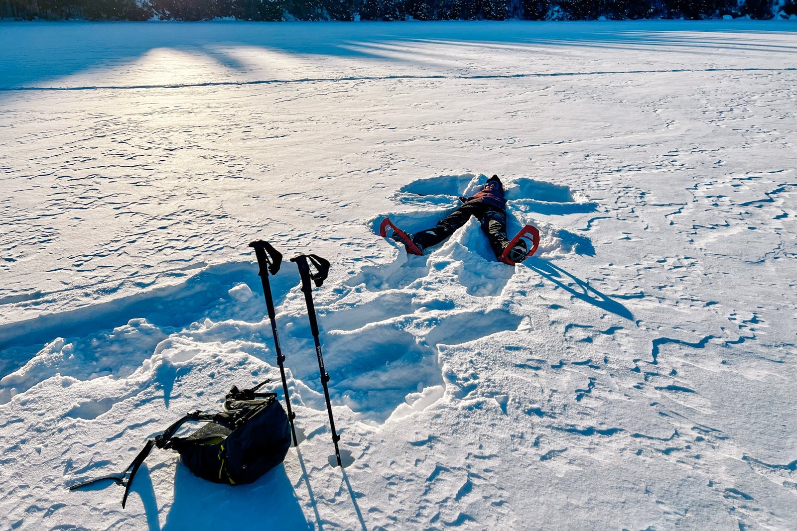 A guide makes a snow angle during a snowshoe outing
