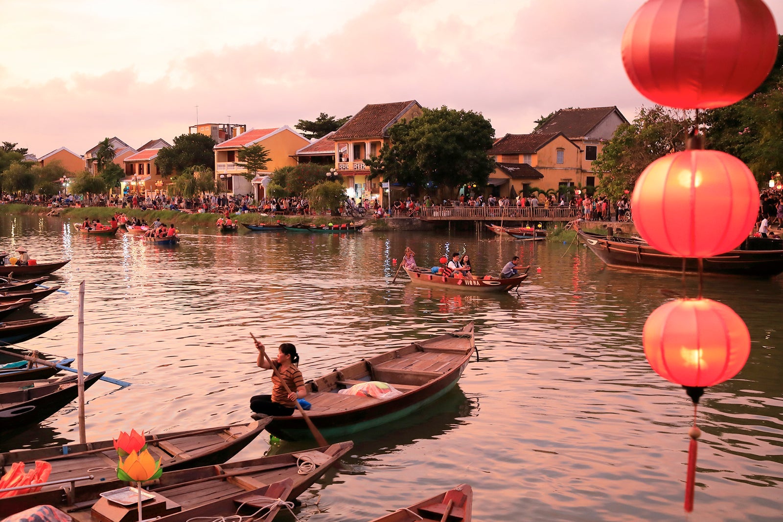 Tour boats docking on the river bank of Thu Bon River with Hoi An old town a UNESCO World Heritage Site in the background.
