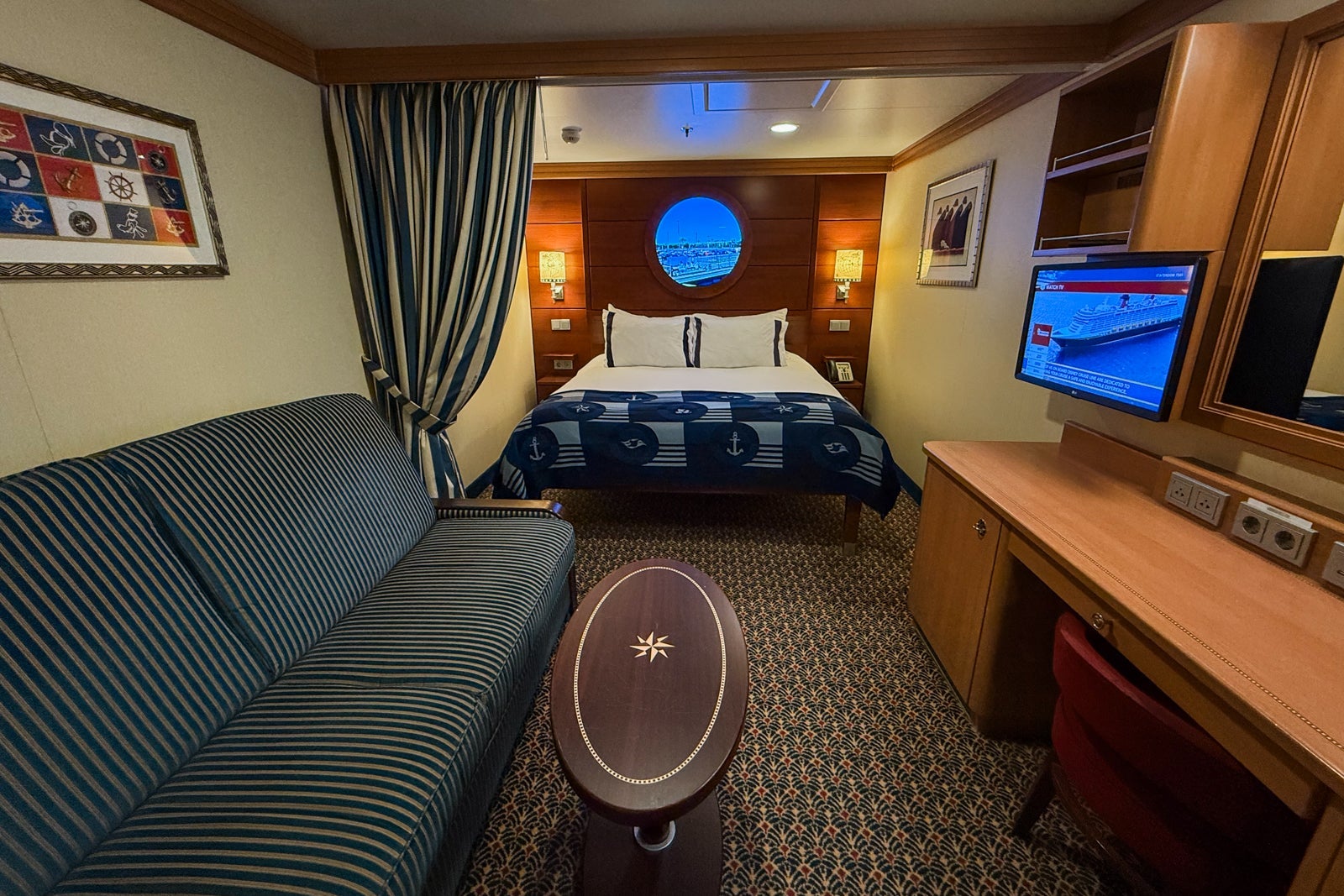 Inside cruise cabin with nautical decor and fake porthole window