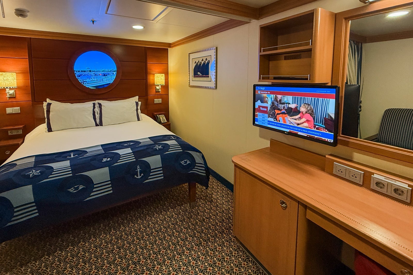 Inside cruise cabin with nautical decor and fake porthole window