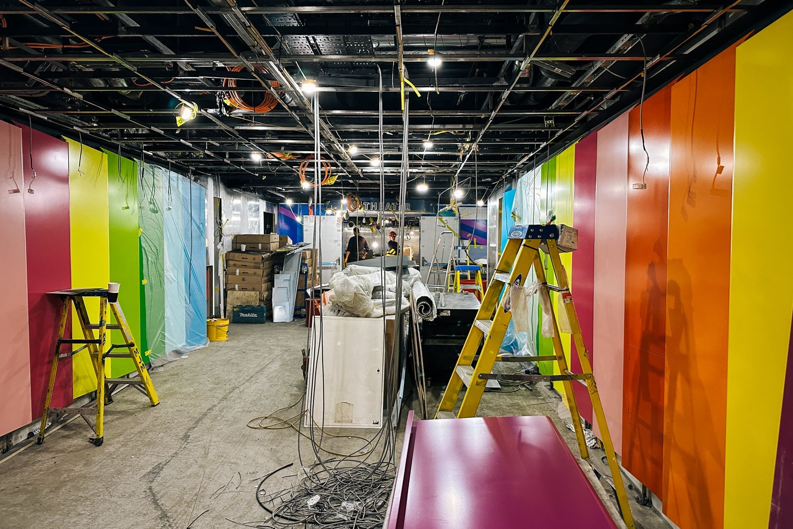 A room with rainbow walls that's under construction on a cruise ship