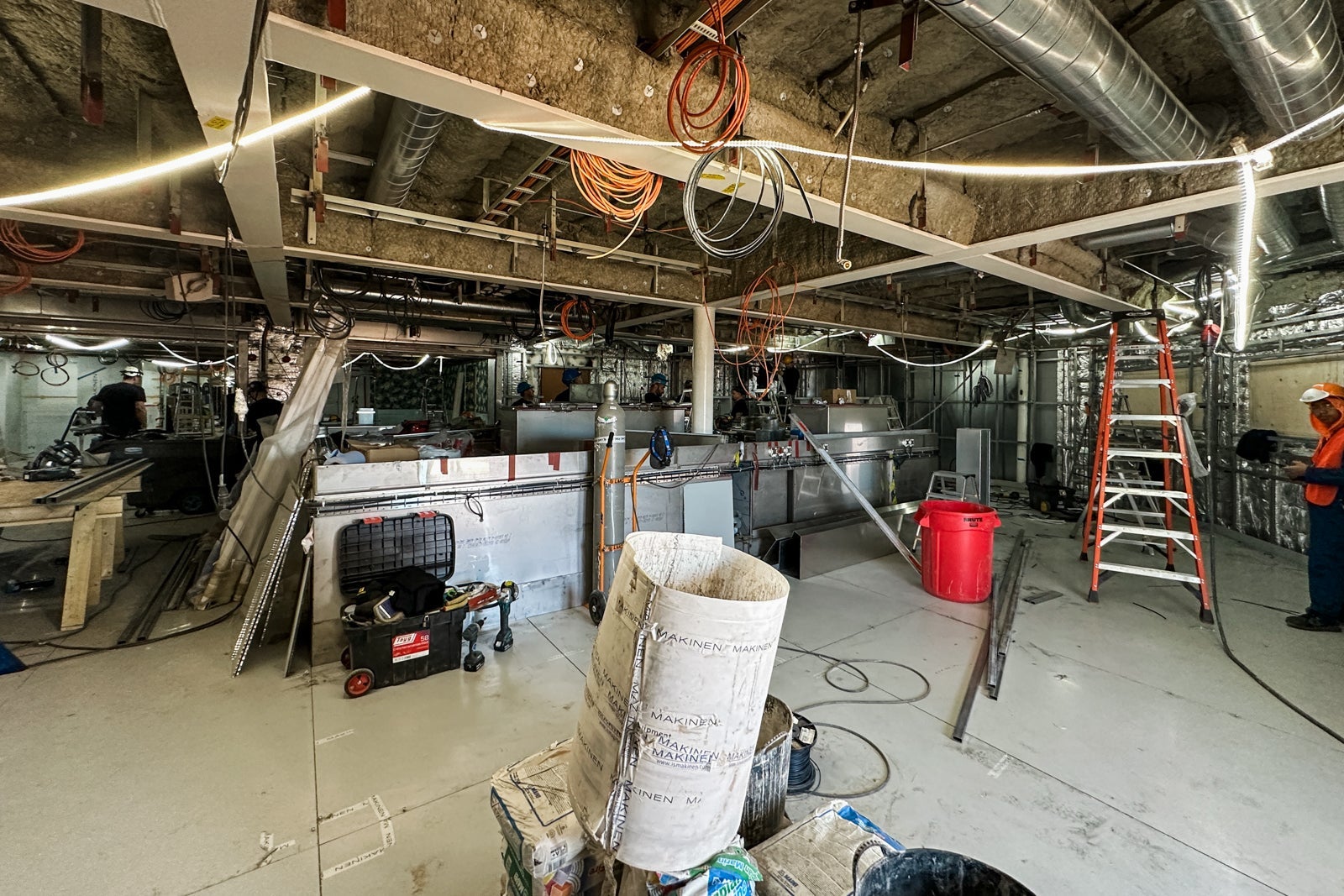 A cruise ship restaurant under construction with hanging wires, a ladder and other tools and equipment