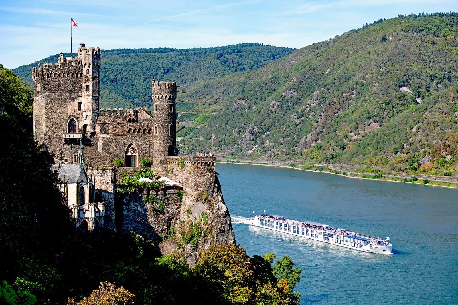 A luxury river cruise glides by a castle
