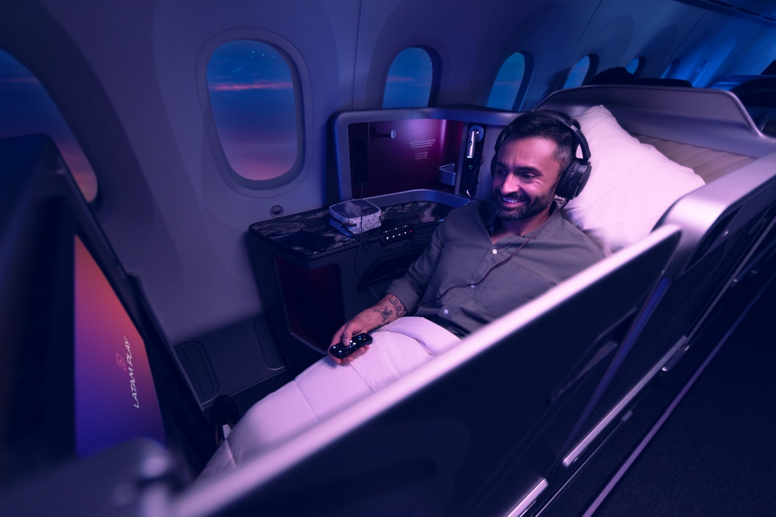LATAM Ricaro business-class seat with door closed and man watching movie
