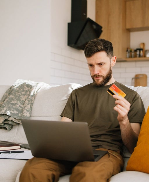 Young military man uses laptop to manage finances well at home