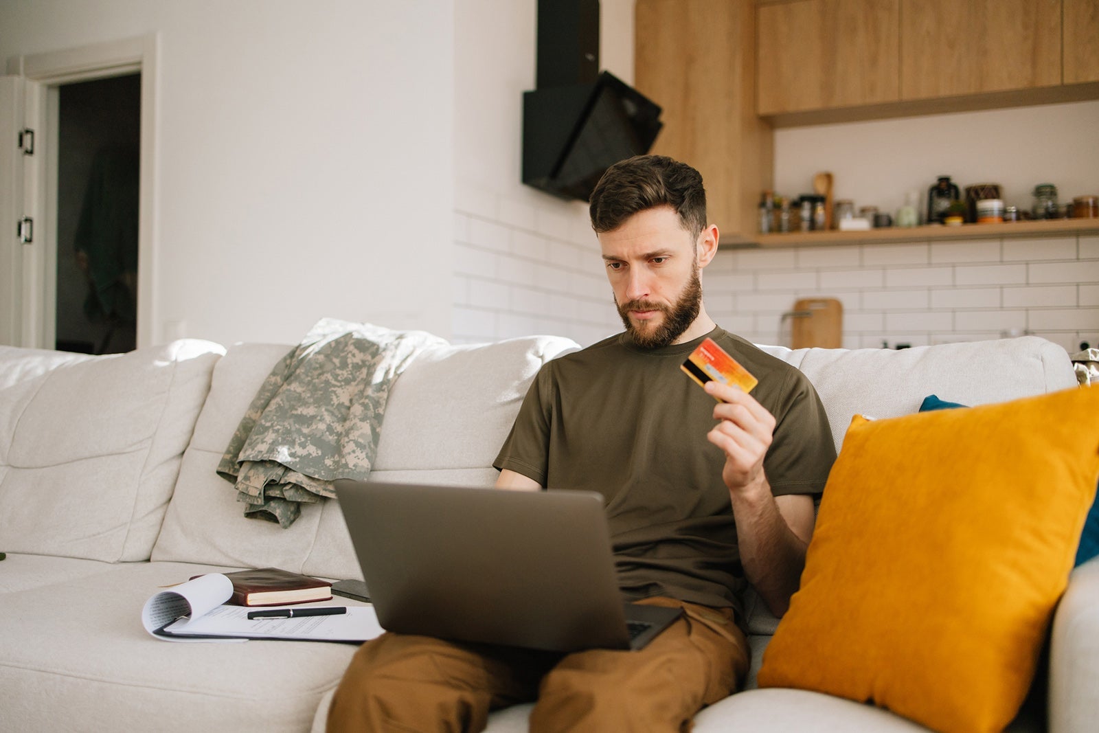 Young soldier manages finances well at home using laptop