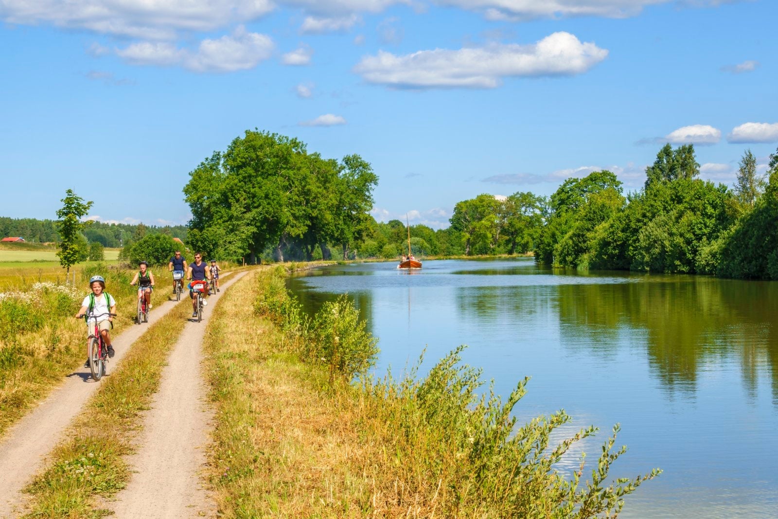 Family cycling on a dirt road by a canal