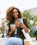 Happy woman enjoying coffee on the street and shopping online