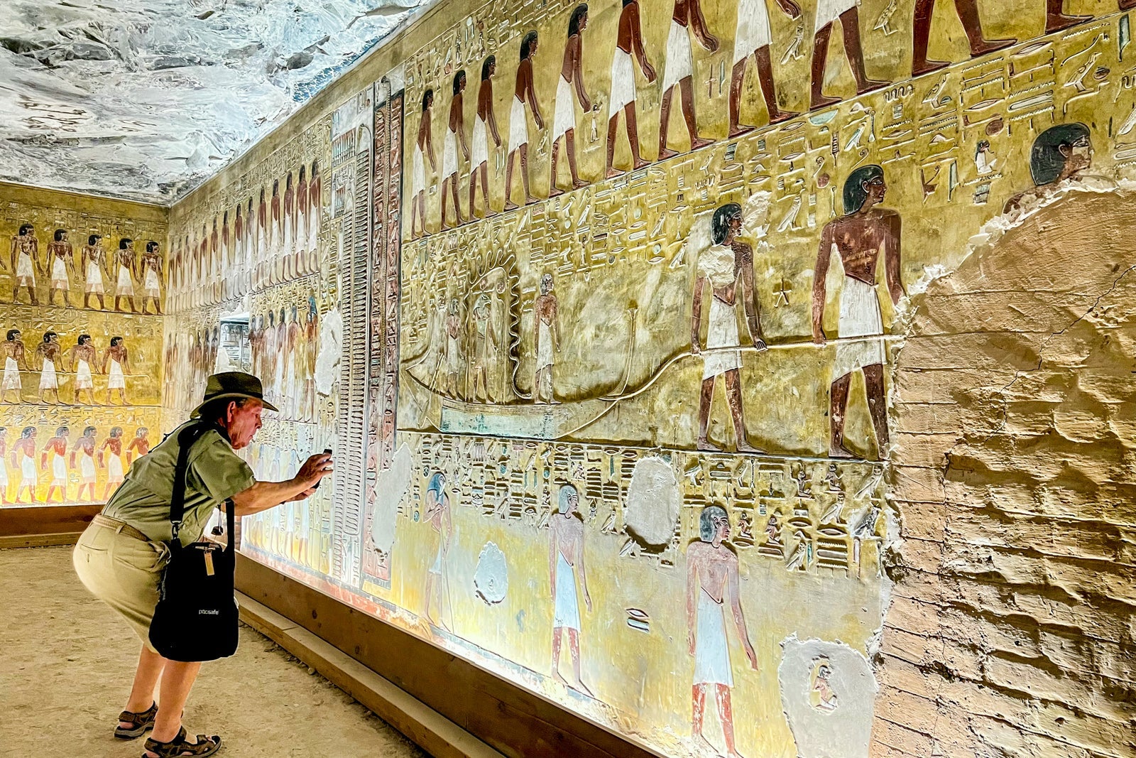A passenger snaps a photo of some of the stunning painted scenes on the walls of the tomb of Seti I