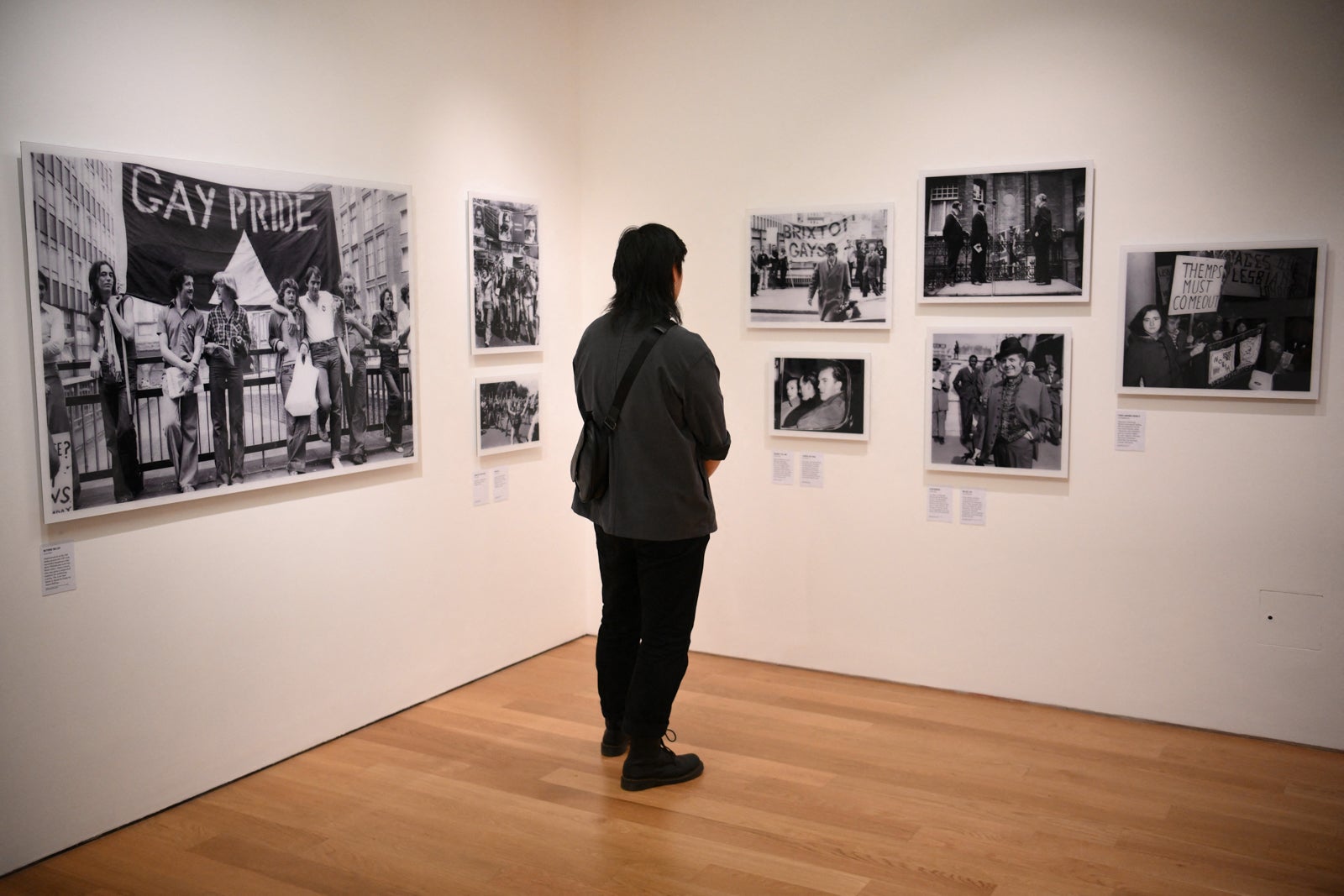 Visitors look at a set of photos displayed in a gallery of the Queer Britain museum, in London