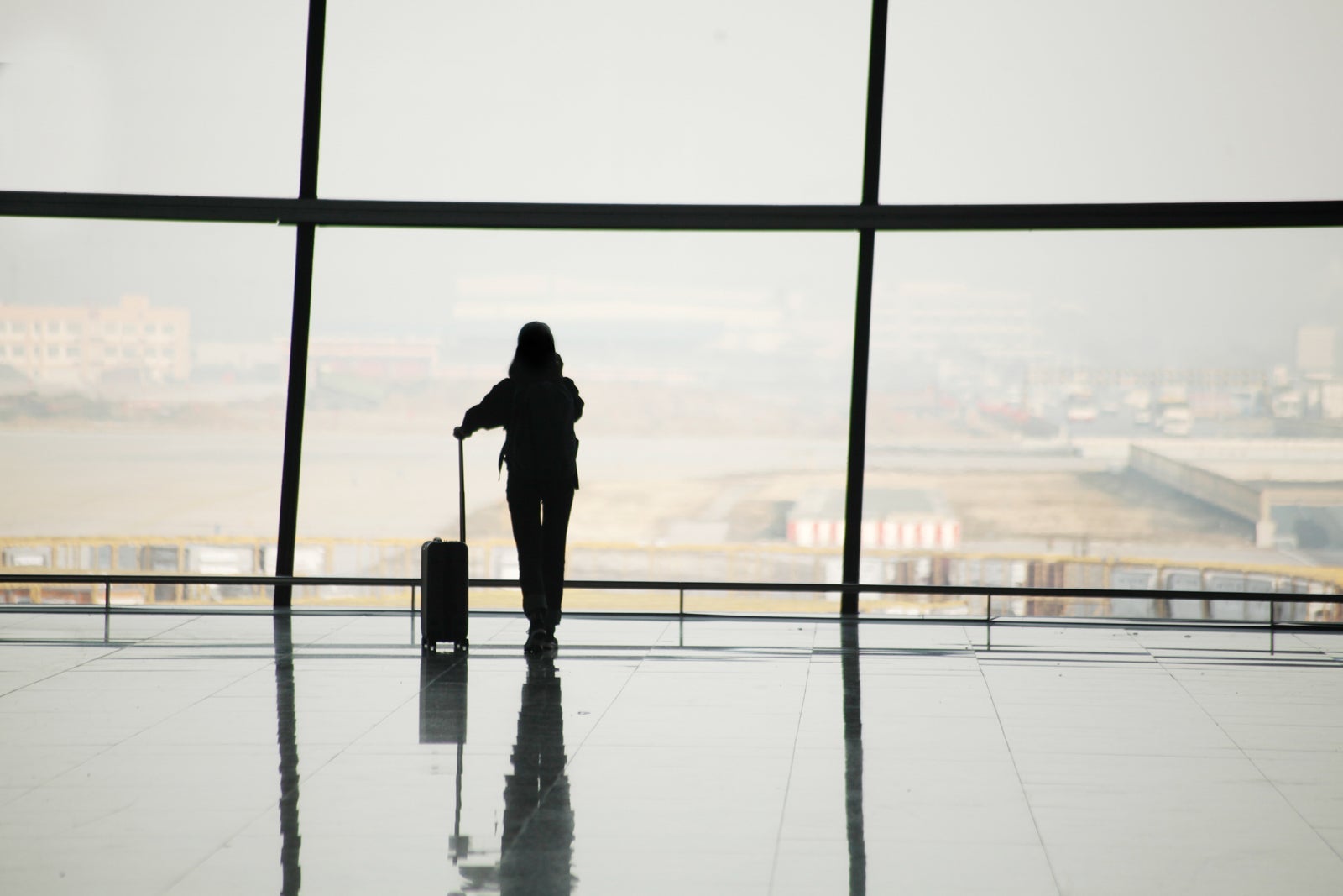 Passenger at airport window with carry-on bag